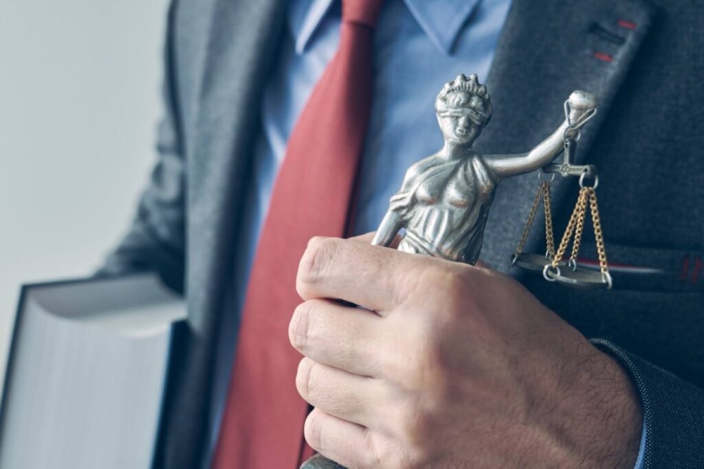 A beneficiary lawyer gripping a statue and holding a law book, ready to defend a client’s inheritance and help answer the question, Can a trustee remove a beneficiary from a trust?